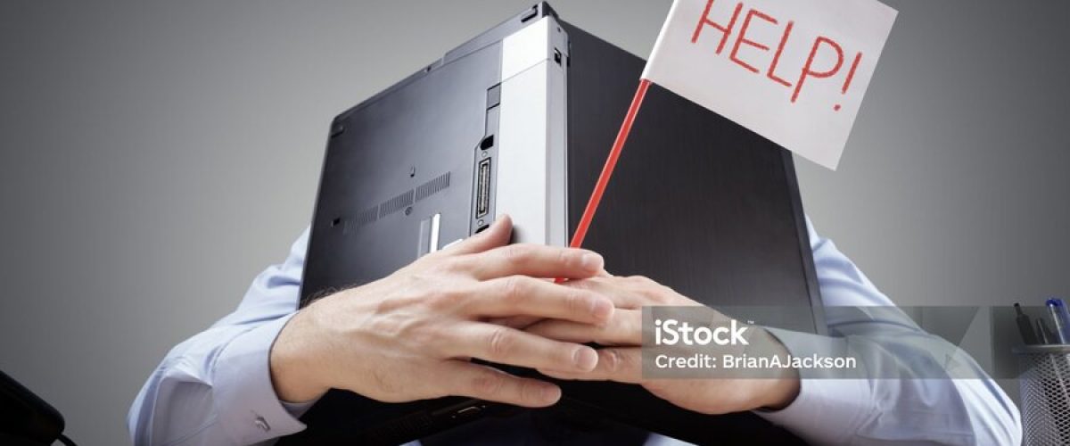 Frustrated and overworked businessman burying his head uner a laptop computer asking for help