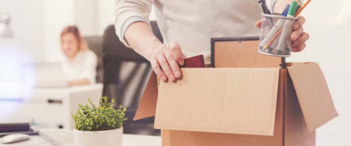 Nothing left behind. Attentive dedicated fired man packing his stuff in a box as he cleaning his workplace before leaving the office